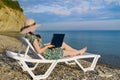 The girl is a freelancer, enjoying the beautiful, open sea.sitting on a sun lounger next to your laptop. the view from the back Royalty Free Stock Photo