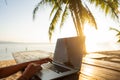 Girl freelancer working on the sea at sunset with a computer