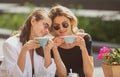 Girl friends in cafe outdoor. Outdoors portrait of two young beautiful women friends drinking coffee. Royalty Free Stock Photo