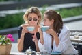 Girl friends in cafe outdoor. Outdoors portrait of two young beautiful women friends drinking coffee. Two beautiful Royalty Free Stock Photo