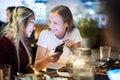 Girl friends having a dinner together at a rooftop bar using a s Royalty Free Stock Photo