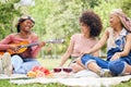 Girl friends, music and guitar at picnic with fruit, drinks and happy laughter in nature. Friendship, song and party on Royalty Free Stock Photo