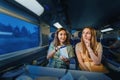Girl friends passengers sitting in first class train at night time, and eating chips