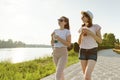 Girl friends are walking in the park in nature. Girls walk along the green lawn, talk, have fun.