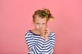 A girl with a funny hairstyle in a striped T-shirt touches her hair, is surprised and makes funny faces