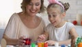 Girl in funny headband putting egg into red food coloring, Easter traditions