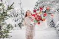 A girl in a fur coat throws Christmas balls to decorate the Christmas tree.Girl throws Christmas decorations from basket