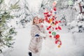 A girl in a fur coat throws Christmas balls to decorate the Christmas tree.Girl throws Christmas decorations from basket