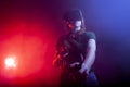 Girl gamer in modern virtual reality glasses plays a shooter on a dark red-blue background, a woman shoots with game joysticks Royalty Free Stock Photo