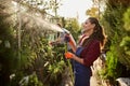 Girl gardener sprays water plants in the beautiful nursery-garden on a sunny day. Working in the garden