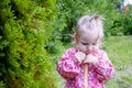 A girl gardener stands near the Christmas trees in a pink jacke. The girl near the tree pondered