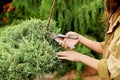 Girl gardener in working clothes and straw hat cuts garden scissors evergreen