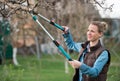 Girl gardener working in the spring garden and trimming tree