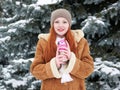 Girl get warm and drink tea in winter park. Fir trees with snow. Royalty Free Stock Photo