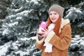 Girl get warm and drink tea in winter park. Fir trees with snow. Royalty Free Stock Photo