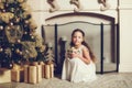 Girl with gift box sitting near christmas tree, vintage toned Royalty Free Stock Photo