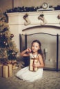 Girl with gift box sitting near christmas tree, vintage toned Royalty Free Stock Photo