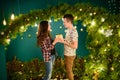 A girl gives her New Year`s gift to a guy, a husband. Loving couple. Christmas decoration Happy New Year. against the background