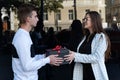 Girl gives to guy black gift box. Young woman gives gift to friend Royalty Free Stock Photo