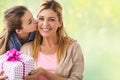 Girl giving birthday present to mother over lights Royalty Free Stock Photo