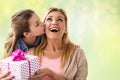 Girl giving birthday present to mother over lights Royalty Free Stock Photo