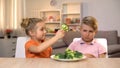 Girl giving brother broccoli, playing with food, unappetizing healthy food Royalty Free Stock Photo