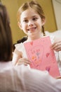 Girl giving mom a drawing.