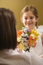 Girl giving mom flowers.