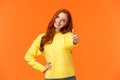 Girl giving permission, say yes. Cheerful redhead woman in yellow sweater extend arm and show thumb-up, smiling nod