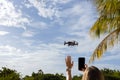 Girl giving stop signal with hand to flying drone and taking photo of it. Selective focus. Royalty Free Stock Photo