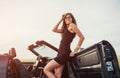 Girl gladly posing next to a black car