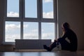 A girl with a glass of wine sits on the floor at a large stained glass window