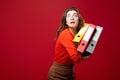 The girl in glasses carries folders, with a fright on her face on a red background. Mood stress, accounting reporting