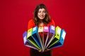 The girl in glasses carries multicolored folders, with fright on face on red background. Mood stress, panic, accounting reporting