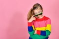 The girl in glasses and a multi-colored sweater on a pink background looks into the caire Royalty Free Stock Photo