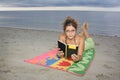 Girl with glasses reading a book in the beach