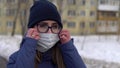 A girl with glasses stands on the street and takes off a surgical mask and breathes a sigh of relief