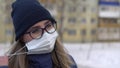 A girl with glasses stands on the street and takes off a surgical mask and breathes a sigh of relief