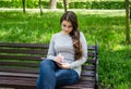 Beautiful young girl in glasses writes with a pen in a notebook while sitting on a bench in a park. Royalty Free Stock Photo