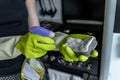 A girl in gloves puts detergent on a sponge and is about to wash the stove. Kitchen cleaning