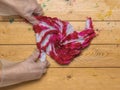 A girl in gloves unfolds a T-shirt painted in tie dye style. Flat lay
