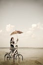 Girl go for a cycle ride at water with umbrella