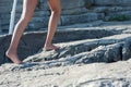 The girl goes barefoot on the rocks, climbing up