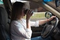 The girl goes behind the wheel of a car holding a paper cup and drinks coffee. Driving a car close up