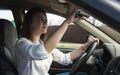 The girl goes behind the wheel of a car and looks in the rearview mirror. Woman driving