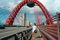 The girl goes over the bridge along the road with cars passing by