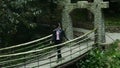 Girl goes on a suspension bridge in a dense forest