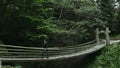 Girl goes on a suspension bridge in a dense forest