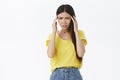 Girl going crazy with head spinning round. Unfocused and confused frustrated tanned female in yellow t-shirt holding