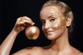 Girl with golden bodyart posing with golden apple